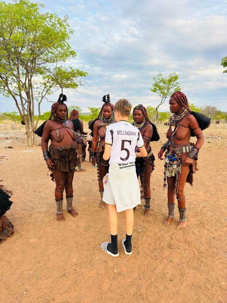 A young visitor being introduced to a group of Himba women in the village