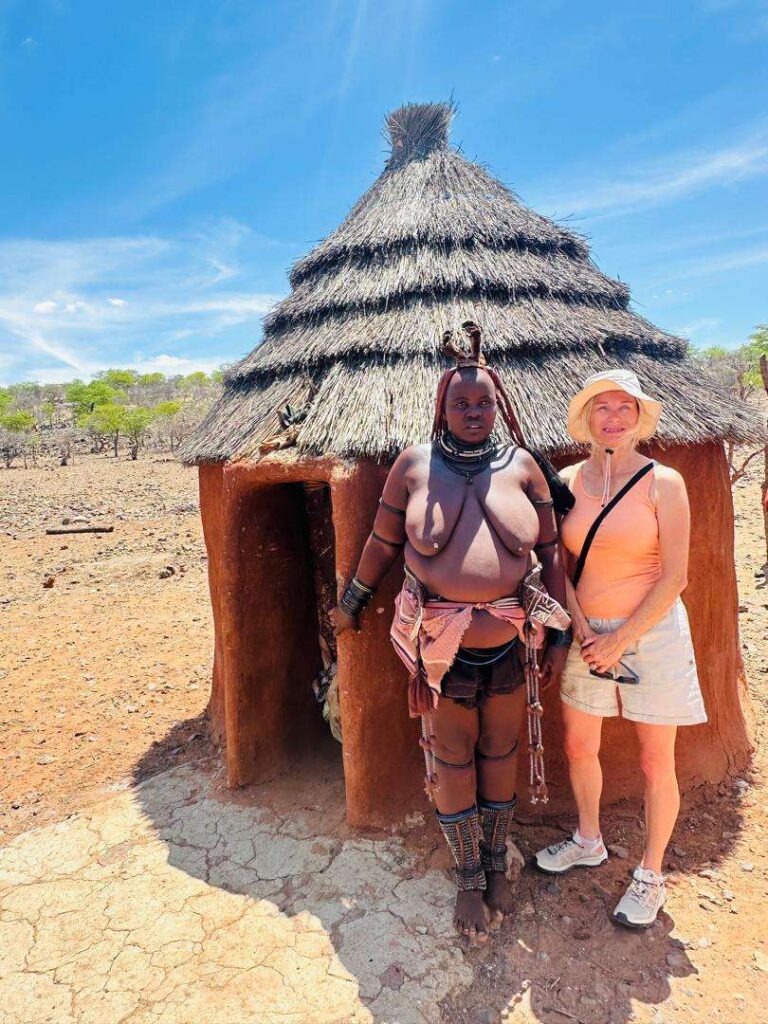A Two Farm guest standing with a Himba woman outside her hut